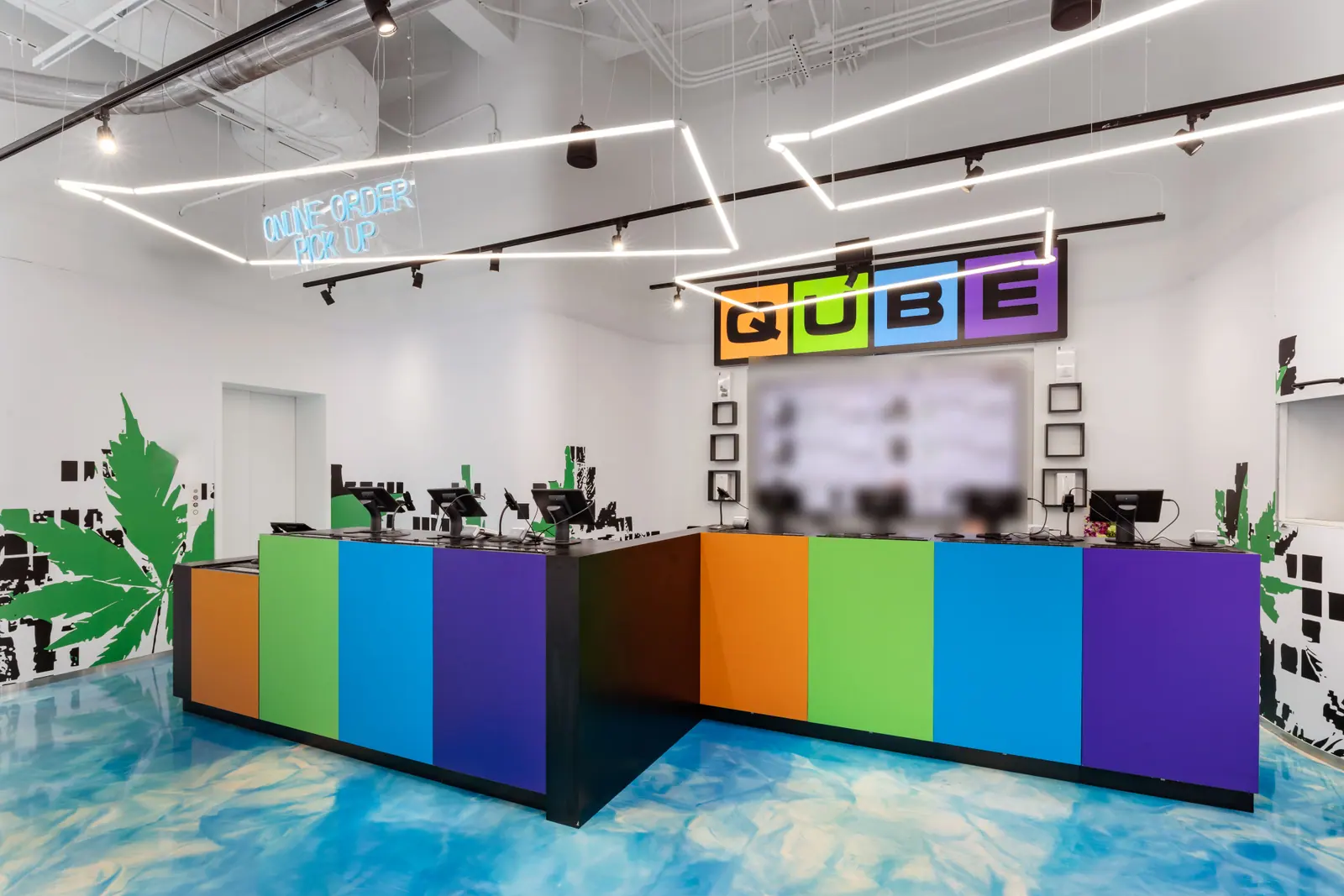 The Qube counter, striped orange, green, blue and purple under the QUBE sign, with an Online Order Pick Up sign in neon